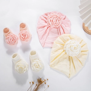 Flachbild von rosa und gelben Baby-Turban-Mützen und passenden Blumensocken mit Rosen
