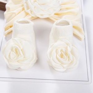 Detail von Baby-Stirnband und Socken-Set mit großen Stoffrosen auf Displaykarte