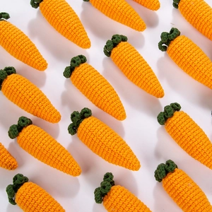 Close-up of hand-crocheted carrot pendants with detailed orange and green knitted textures
