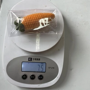 Handcrafted crochet carrot ornament on a scale showing a lightweight 7.5g mass