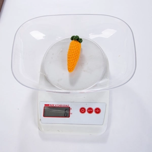 Close-up of hand-crocheted carrot charm showing detailed knit texture on a scale