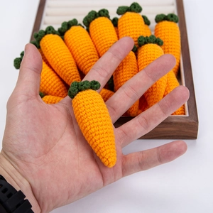 Detailed view of handmade crochet carrot pendants with vivid orange and green yarn texture