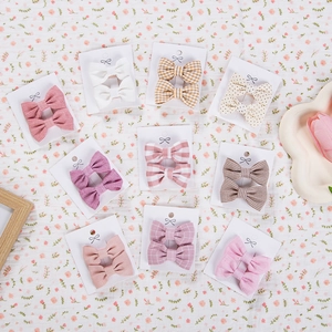 Detailed set of 10 pairs of floral and solid cotton bow clips on a display card