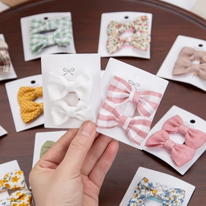 Detailed close-up of floral cotton bow hair clips set on white cardboard packaging