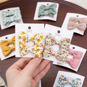 Detailed close-up of floral fabric bow hair clips for girls on a wooden background