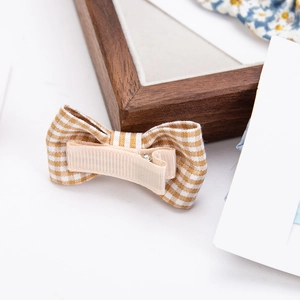 Detail view of cotton gingham hair clip featuring a beige fabric wrapped metal alligator clip