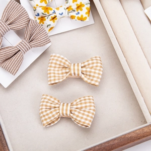 Detailed set of floral cotton bow hair clips in yellow and brown on display card