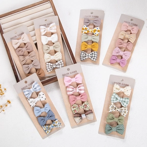 Detail view of cotton bow hair clips set with floral and plaid patterns for infants