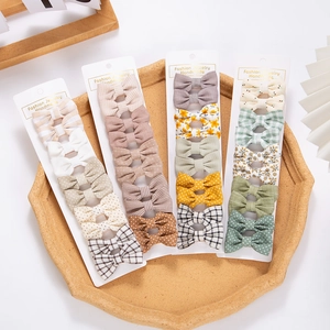 Lot détaillé de barrettes en coton à fleurs et carreaux pour bébés sur un plateau de vente