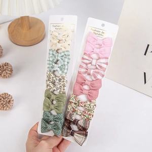 Vue détaillée du lot de 10 barrettes bébé avec nœuds en coton fleuri et motifs à carreaux
