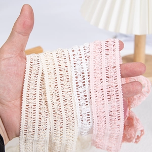 Dettaglio di fasce in pizzo di cotone morbido in crema, bianco e rosa per neonati