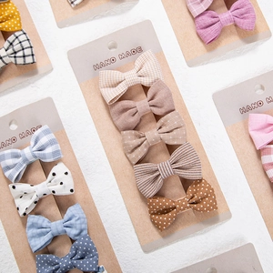 Close-up of five cotton handmade bow hair clips with polka dots and plaid on display card