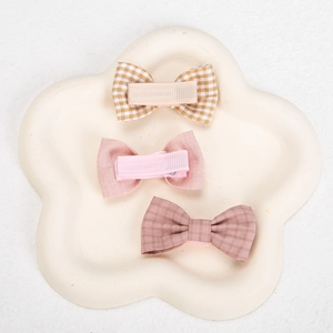 Detail of three handmade fabric bow hair clips for kids on a white decorative floral tray