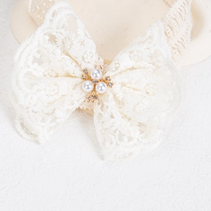 Dettaglio della fascia in pizzo per neonati con perle bianche e accenti di strass brillanti