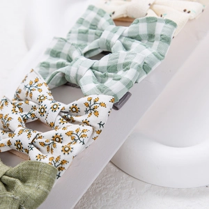 Détail de barrettes nœuds en coton fleuri et à carreaux sur support d'affichage blanc