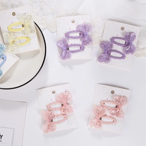 Detail of glitter heart and bow hair clips in assorted pastel colors for girls