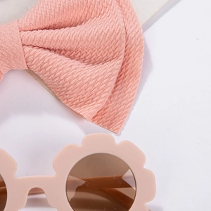 Detailed shot of pink waffle knit bow headband and flower-shaped kids sunglasses set