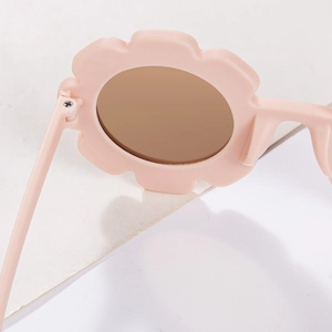 Close-up of light pink flower-shaped sunglasses frame with metal hinge detail