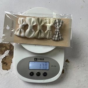 Weight measurement of 5-piece fabric bow hair clips set on electronic scale showing 17g