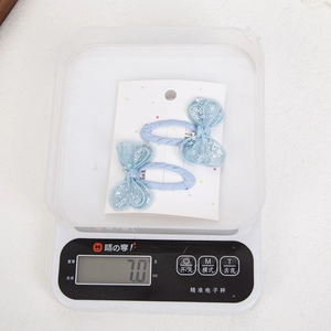 Close-up of light blue sequined butterfly hair clips for girls on a digital scale