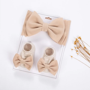 Detailed close-up of baby waffle knit bow headband and matching socks on a white card