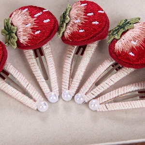 Dettaglio del fermaglio fragola ricamato 3D con filo rosa avvolto e perla decorativa