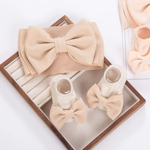 Detail of baby headband and socks set in beige waffle fabric on wooden display tray