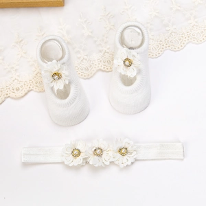 Détail de l'ensemble bandeau et chaussettes pour bébé avec fleurs en dentelle et perles