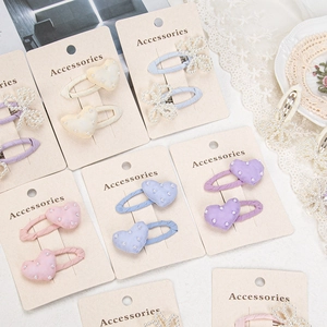 Detail view of pearl bow and heart hair clips set on Accessories card in pastel colors