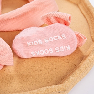 Close-up of pink waffle knit baby socks with anti-slip dots and matching bow headband