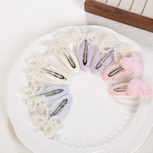 Close-up of pastel pearl bow and heart hair clips on a white ceramic plate