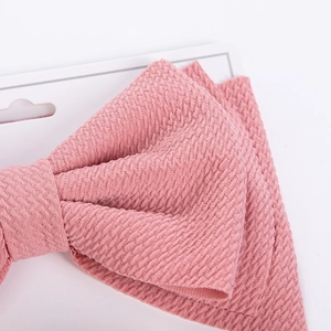 Close-up of pink textured fabric bow with diamond weave pattern on display card