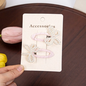 Detail of pink satin-wrapped BB clips with handcrafted white imitation pearl butterflies