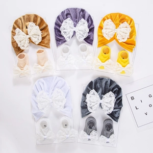 Détail d'un ensemble bonnet et chaussettes en velours pour bébé avec nœuds en dentelle