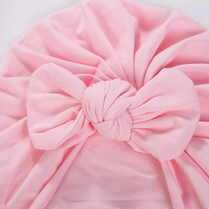 Close-up of pink baby turban hat with a knotted bow design made of soft knit fabric