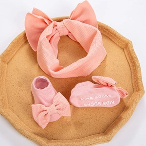 Three-piece baby accessory set featuring peach waffle knit bow headband and matching socks
