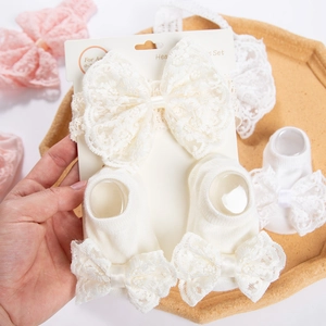 Vue détaillée de l'ensemble bandeau à nœud en dentelle crème et chaussettes pour bébés