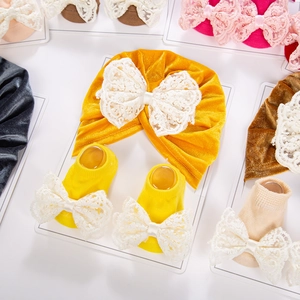 Détail d'un ensemble bonnet turban et chaussettes bébé en velours doré avec dentelle