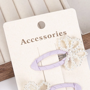 Detail view of purple fabric bow hair clips with pearl butterfly decor on display card