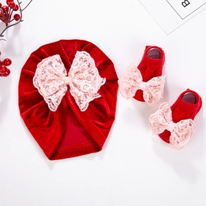 Détail d'un turban rouge pour bébé et de chaussettes assorties avec des nœuds en dentelle