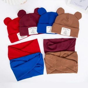 Flat lay of baby bear ear hats and scarves in four colors on a white background
