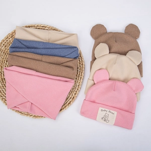 Flat lay of baby bear knit hats and scarves in pink, beige, and coffee colors