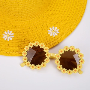 Close-up of yellow daisy floral sunglasses with a woven straw beach hat for summer
