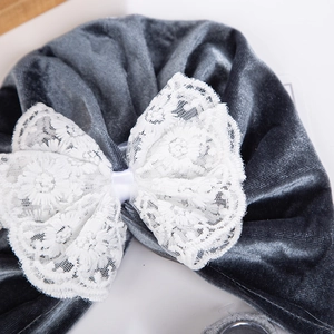 Gros plan détaillé du bonnet turban en velours gris avec un nœud en dentelle blanche