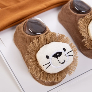 Close-up of brown knit baby floor sock featuring a cute 3D lion applique with fringe mane