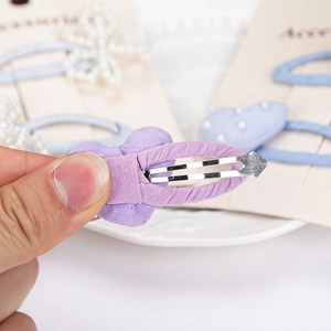 Handheld view of sweet bow hair clip with pearls and fabric wrap on card