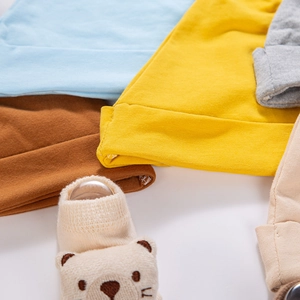 Detailed view of soft knitted baby beanies in various colors with cute 3D bear sock