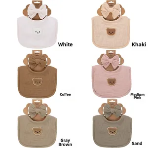 Detailed view of baby cotton gauze bibs and headbands in six earthy tones with bear embroidery