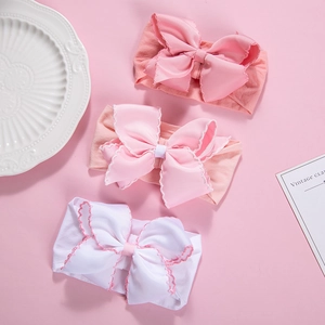 Three soft nylon baby headbands with large ribbed bows in pink and white detail