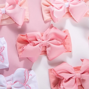 Detailed macro view of soft ribbed polyester bow hairbands with elastic nylon edges for infants